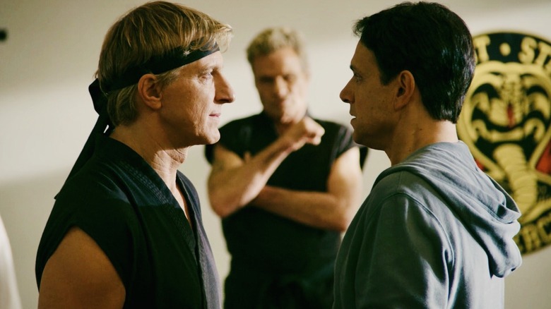 Johnny Lawrence and Daniel LaRusso face off while John Kreese looks on in Cobra Kai