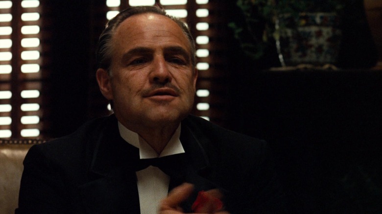 Don Corleone in The Godfather, smiling from his desk.