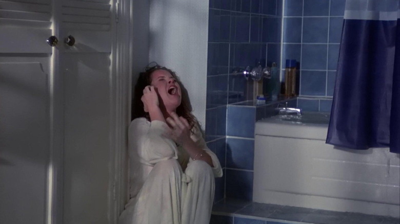 A crouching woman screams in a bathroom