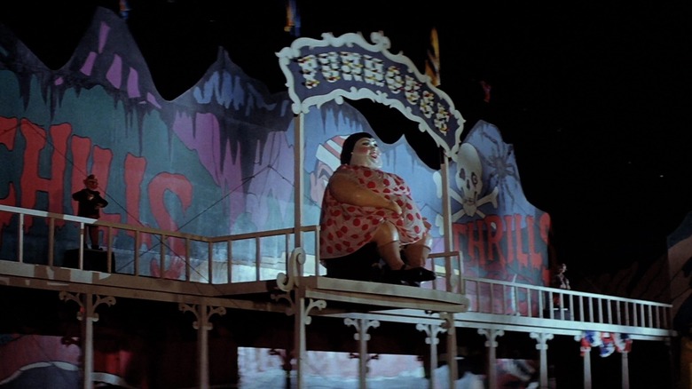 A figurine of a fat lady sits in front of a Funhouse sign