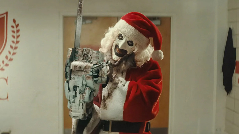 Art the Clown in a Santa costume, in a locker room with a chainsaw, from Terrifier 3