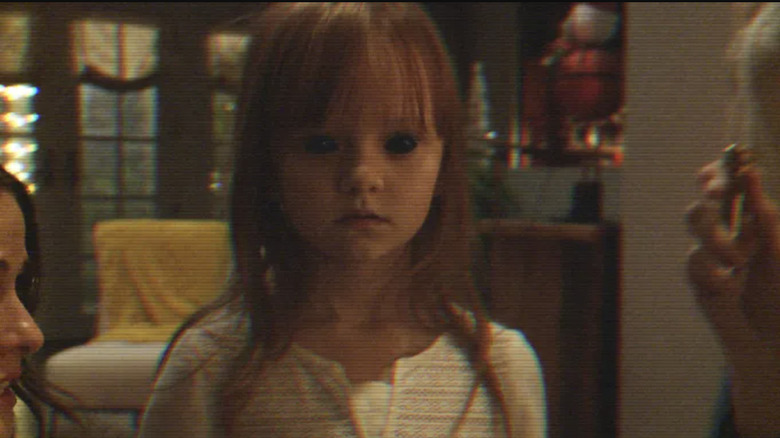 Leila stares at the camera with black eyes, possessed, in Paranormal Activity: The Ghost Dimension