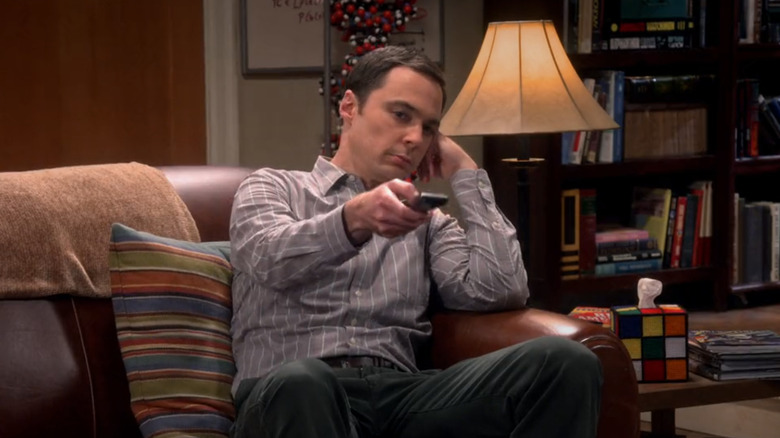 Jim Parsons in the role of Sheldon Cooper sitting on the sofa carries remote control in the theory of the big explosion