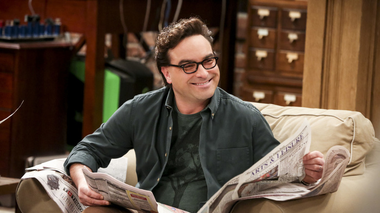 Leonard smiling and reading a newspaper on The Big Bang Theory