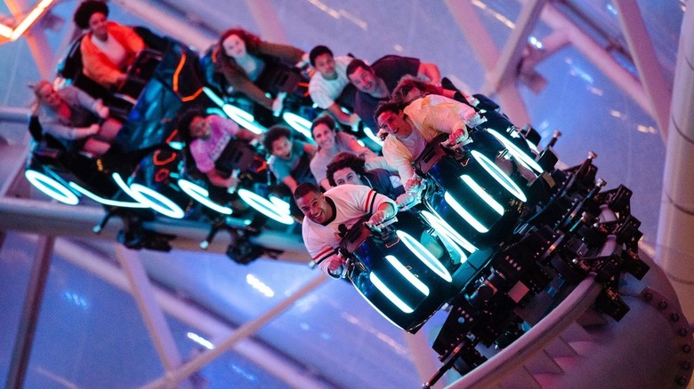 A promo shot of the TRON lightcycle ride, with excited passengers on board as it banks into a turn