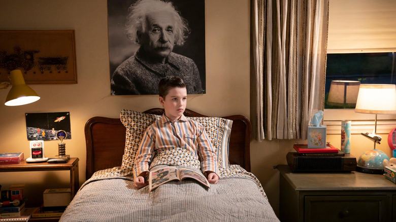 Sheldon Iain Armitage duduk di tempat tidurnya dalam episode Young Sheldon Teenager Soup dan Little Ball of Fib