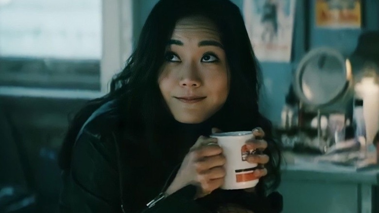 Kimiko sostiene una taza de café y les sonríe a los chicos.