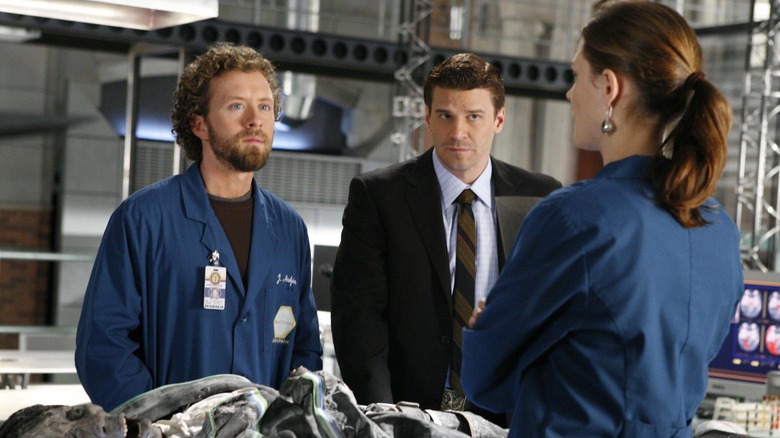 Hodgins, Booth, and Brennan standing around a corpse on Bones