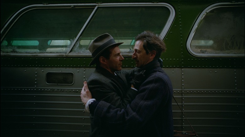 Attila (Alessandro Nivola) and László (Adrien Brody) embrace in front of a bus in The Brutalist