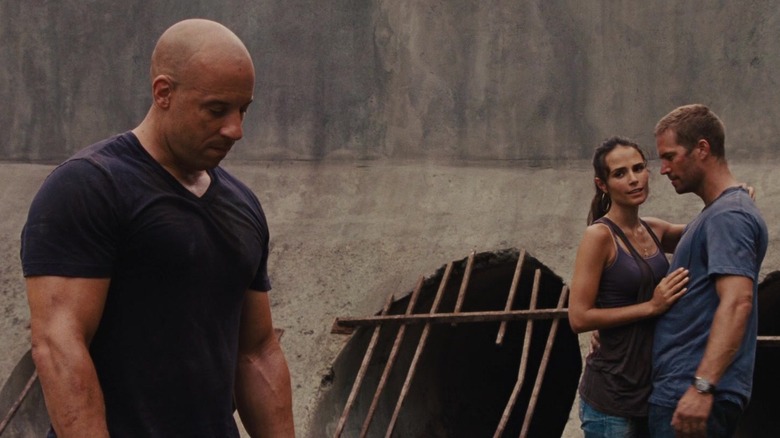 Dom standing by an embracing Mia and Brian in Fast Five