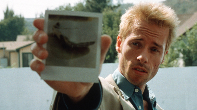 Guy Pearce segura uma polaroid como Leonard Shelby em Memento