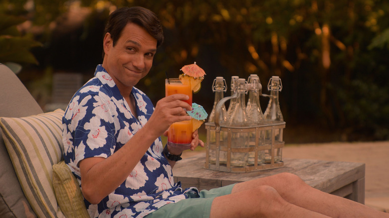 Daniel LaRusso lounging by the pool and raising a cocktail in salute on Cobra Kai