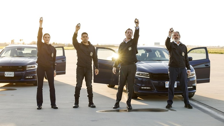 A group of officers holding their badges up in the air on NCIS