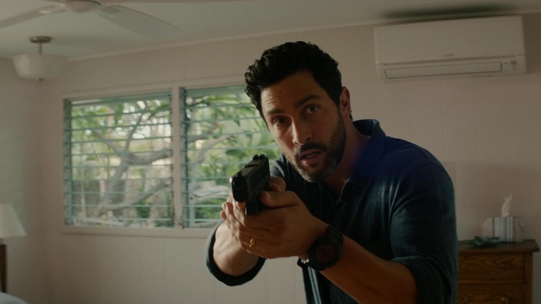 Jesse Boone holding a gun as he stares intensely in NCIS: Hawai'i