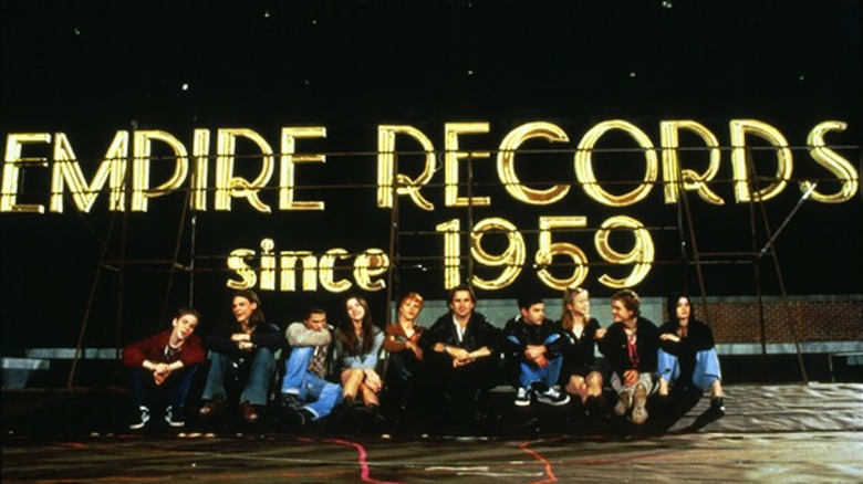 The cast of "Empire Records" pose for a photo with the eponymous record store's signage.