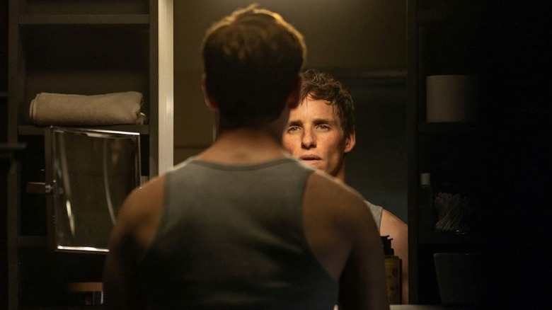 Eddie Redmayne looks in the mirror as the Jackal in The Day of the Jackal