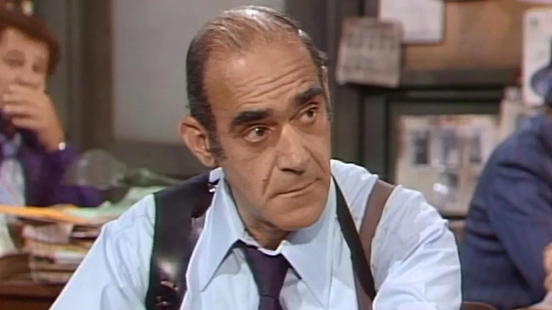 Abe Vigoda as Sergeant Philip K. Fish sitting at his desk on Barney Miller