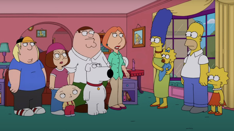 The Griffin and Simpsons family stand together in the Simpsons living room.