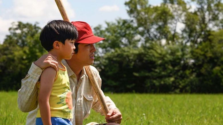 Alan Kim and Steven Yeun stand in a field in Minari