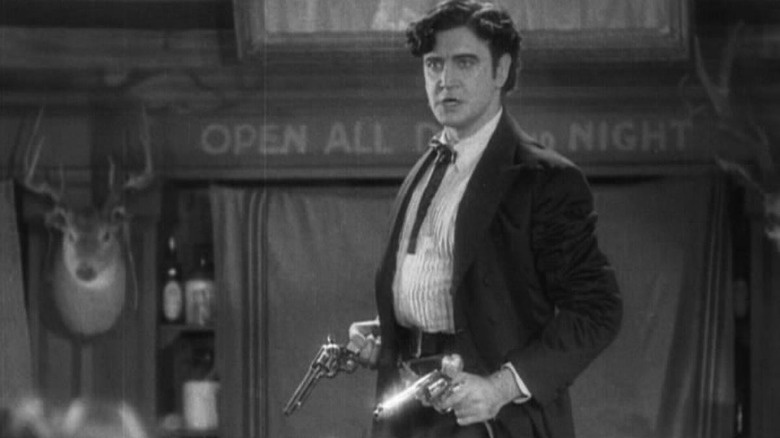 Yancey Cravat holding two guns, and ready to use them.