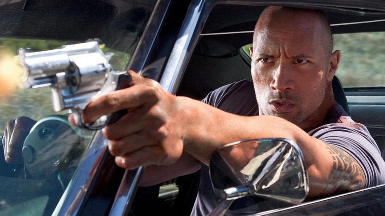 Dwayne Johnson como Jimmy Cullen dispara un arma mientras conduce más rápido