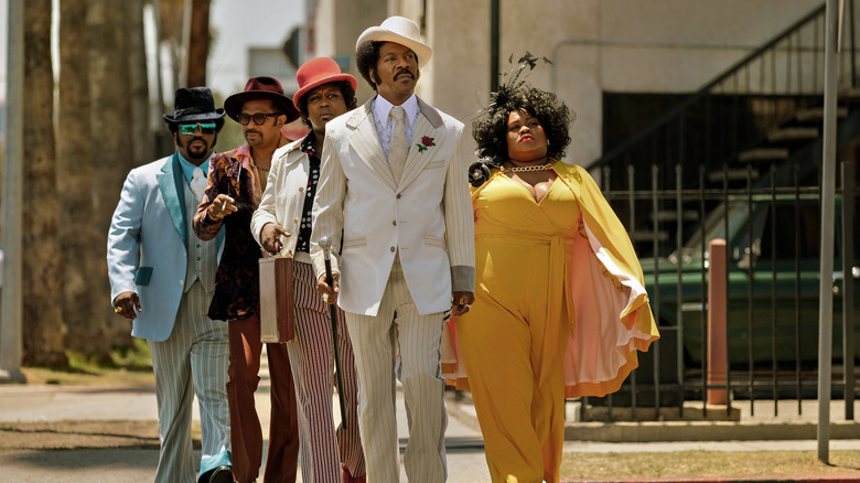 Eddie Murphy as Rudy Ray Moore, walking down the street with his 1970s entourage