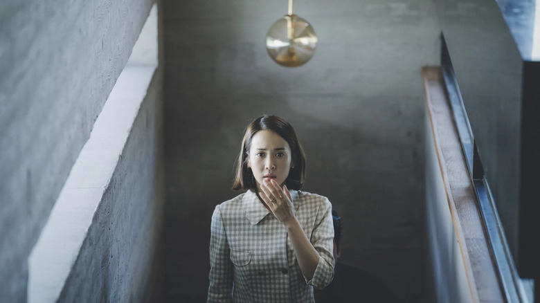 Yeon-gyo with her hand covering her mouth coming up the stairs in Parasite