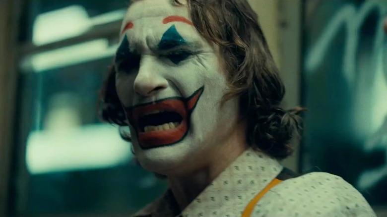 A close-up of Joaquin Phoenix as Arthur Fleck/The Joker crying and wearing white, red, and blue clown makeup in Joker