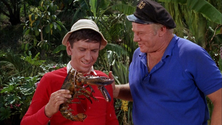 Gilligan holding a live lobster. The Skipper, standing next to him, seems to be proud of him.