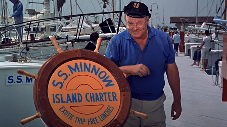 Alan Hale Jr.'s Captain Jonas Grumby stands alongside a wheel with the name of the S S Minnow in Gilligan's Island