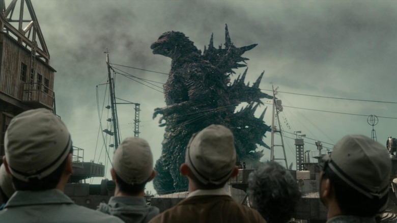 Soldiers looking up at Godzilla as he walks through the bay in Godzilla Minus One