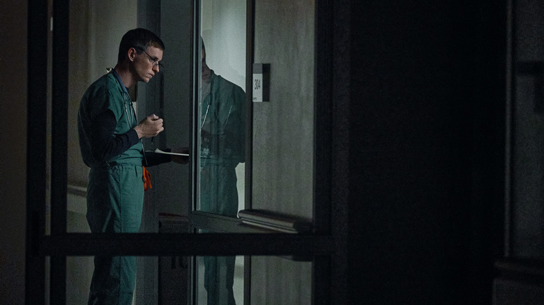 Nurses Charles Cullen (Eddie Redmayne) stands at the edge of a hospital room in "The Good Nurse" (2022)