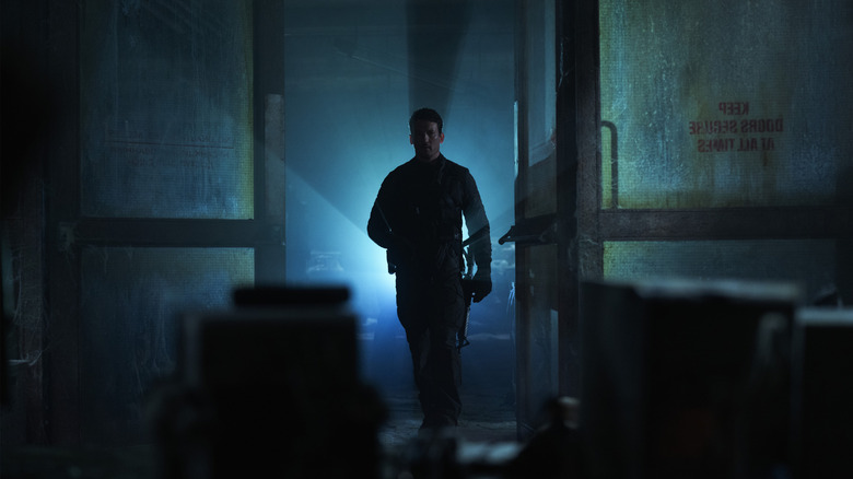 Miles Teller como Levi em um misterioso bunker iluminado por iluminação nítida no desfiladeiro