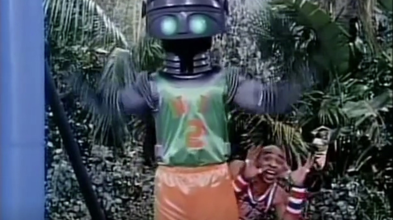 A member of the Harlem Globetrotters hides behind a robot in The Harlem Globetrotters on Gilligan's Island