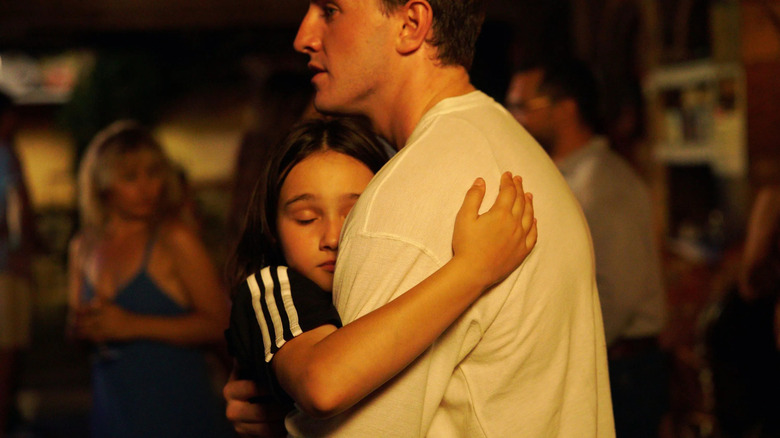 Sophie (Frankie Corio) tightly hugs her father Calum (Paul Mescal) with her eyes shut, resting her head against his chest in Aftersun