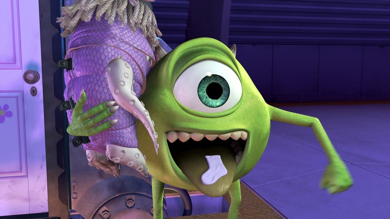 Mike Wazaowski is sticking out his tongue. There is a sock in his mouth. He has a little girl slung over his shoulder. From Monsters, Inc.