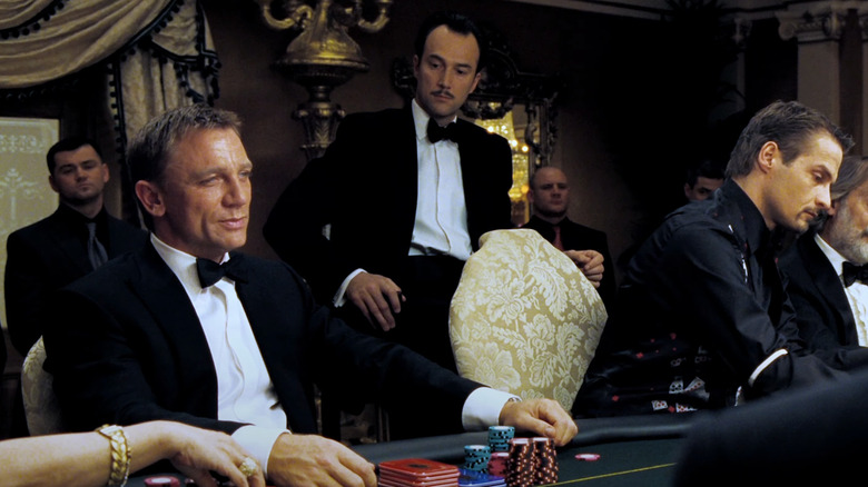 Daniel Craig's James Bond sits at the poker table surrounded by people in Casino Royale