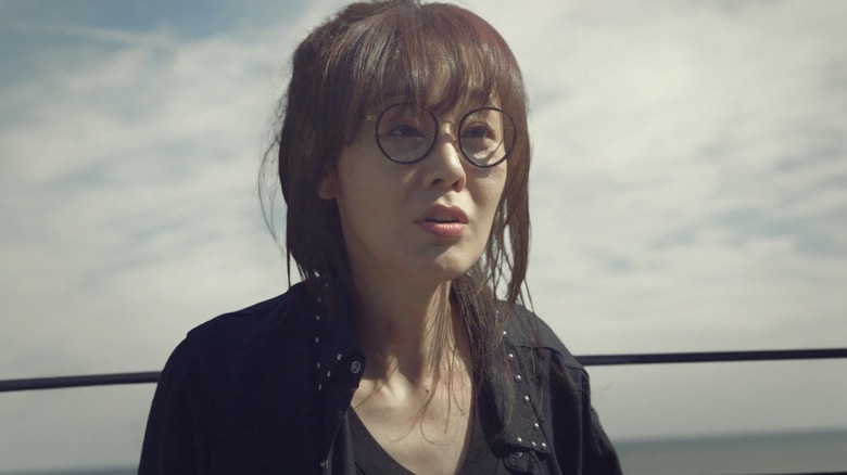 Ma Ji-won (Kim Yunjin) wears glasses while standing on a dock in Ms. Ma, Nemesis