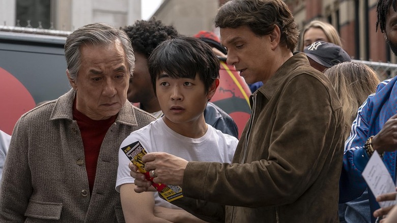 Mr. Han, Li Fong, and Daniel LaRusso looking at a pamphlet in Karate Kid: Legends