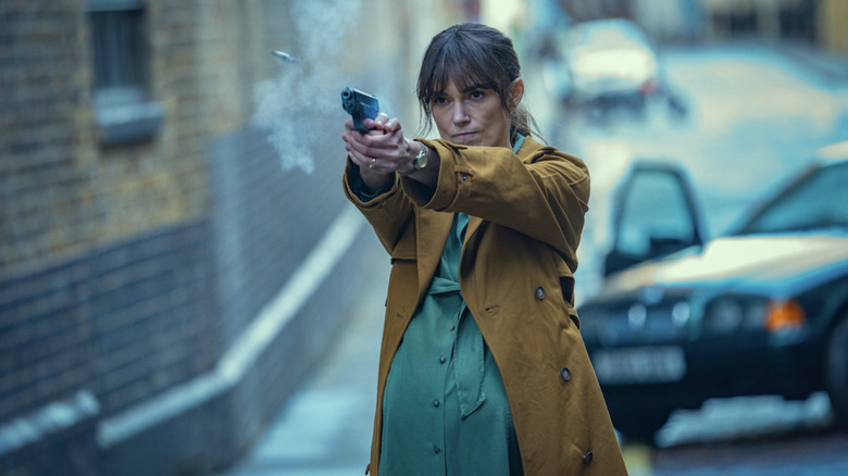 Keira Knightley's Helen Webb stands in front of a car and fires a gun in Black Doves