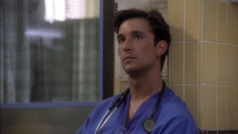 Noah Wyle as John Carter leaning up against a pillar in ER Season 2