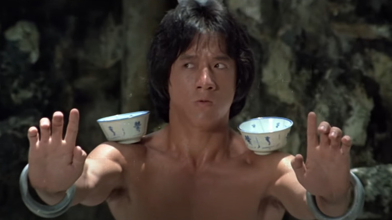 Wong Fay-Hung (Jackie Chan), in a fighting position, balanced tea on the head and hands in the drunken master