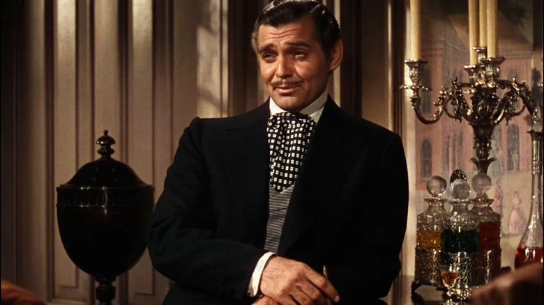 Rhett Butler, in a suit, standing by a tray of booze bottles in Gone with the Wind