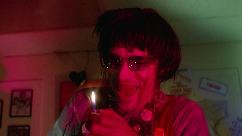 Chop Top in a wig, looking at a cigarette lighter, in The Texas Chainsaw Massacre 2