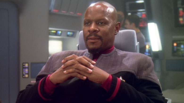 Benjamin Sisko folds hands in captain's chair