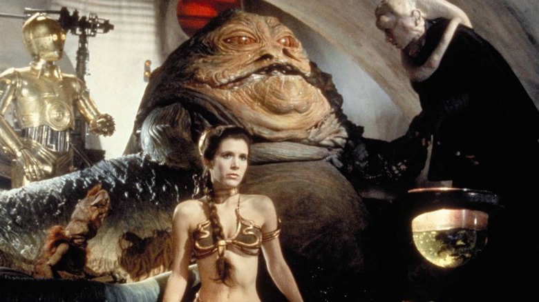 Princess Leia Organa sits in gold bikini beside Jabba the Hutt