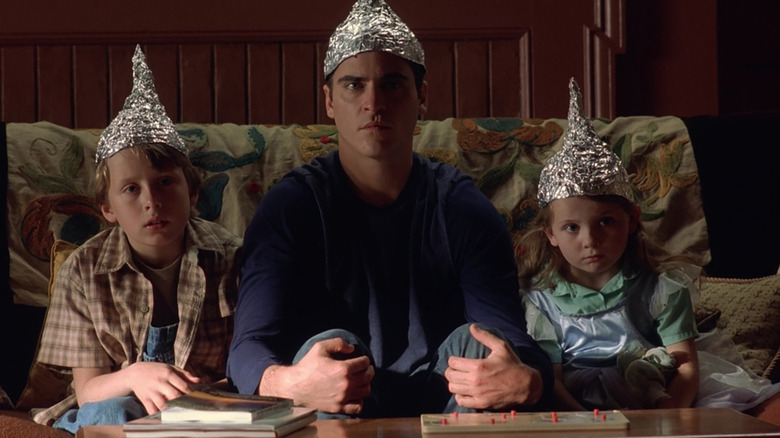 Rory Culkin, Joaquin Phoenix, Abigal Breslin on couch in foil hats in Signs