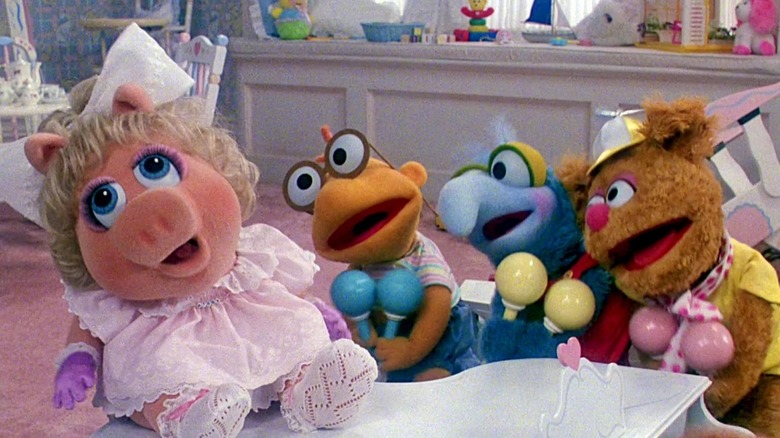 Infant versions of Miss Piggy, Scooter, Gonzo, and Fozzie Bear sitting next to each other, holding pairs of maracas