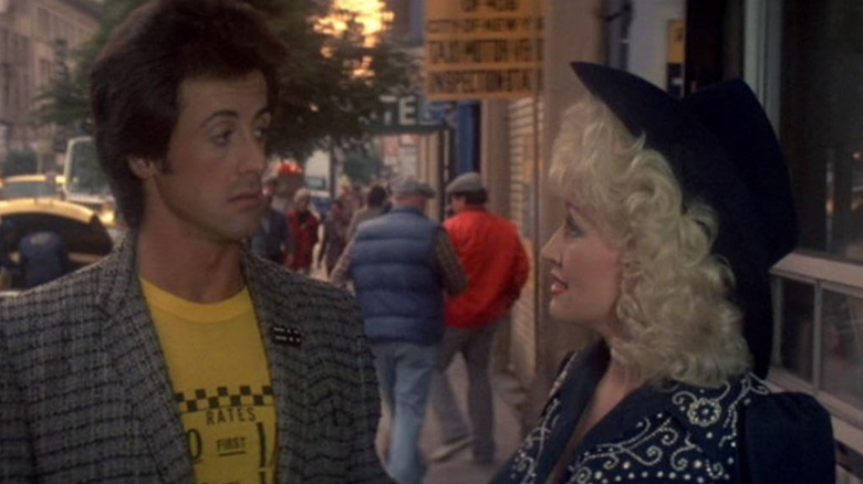 Jake (Dolly Parton) and Nick (Sylvester Stallone) talking on the sidewalk in Rhinestone