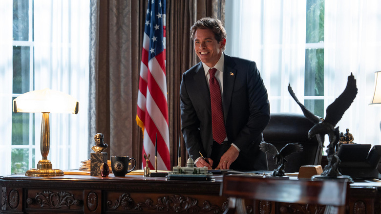 James Marsden as President Bradford smiling while signing a document in Paradise